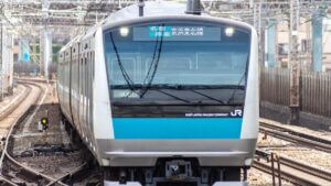 Front view of a JR East commuter train on curved tracks, blue stripe along the nose.